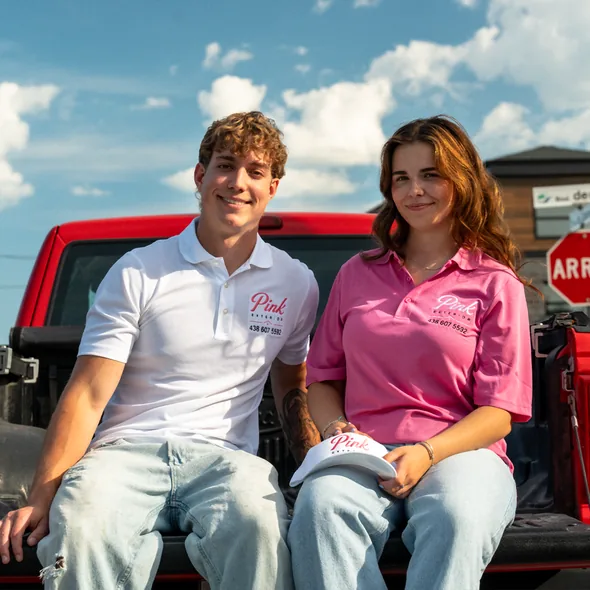 Deux membres de l'équipe sont assis sur la boîte du camion Pink Exterior.