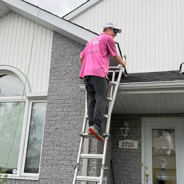 Un technicien monte à l'échelle devant une maison.