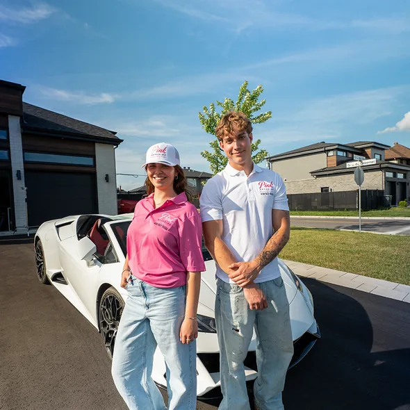 Deux membres de l'équipe Pink Exterior se tiennent près d'une voiture blanche dans une entrée.